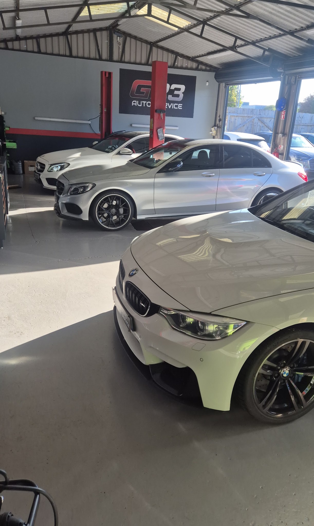 Inside the G23 Auto Service workshop in Ashbourne, two cars on the floor and the G23 sign on the wall